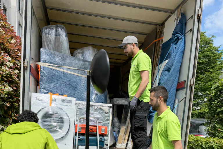 Zwei Umzugshelfer laden verpackte Möbel und Kartons in einen Transporter